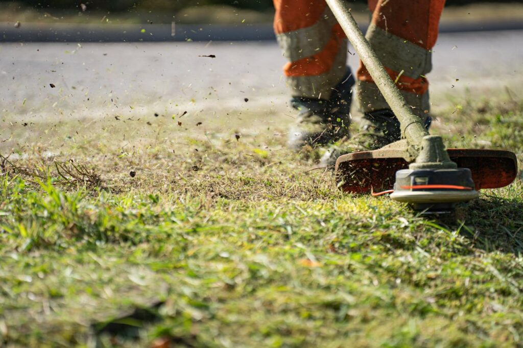 A Person in Orange Pants Cutting Grass with a Grass Cutter